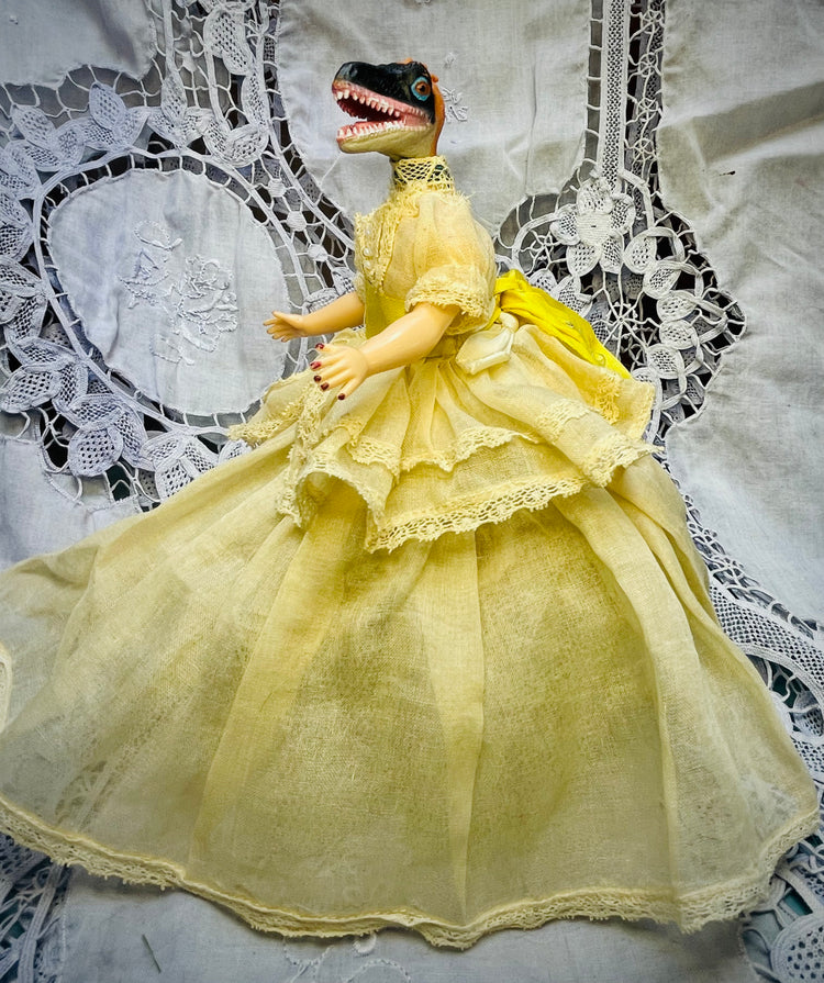 Plastic vintage doll in a very elegant lace dress with tulle underskirt. Toy dinosaur head. 6" tall 5" wide. 