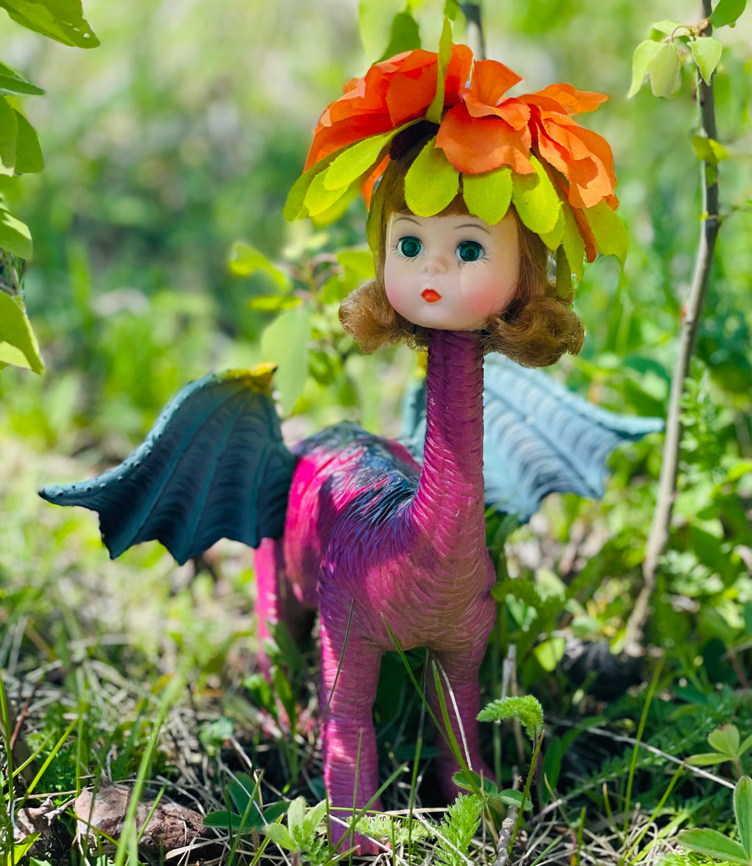 Four legged vintage toy dinosaur with wings and Madame Alexander doll head topped with flower headdress. 9' Tall, 8" long, 7" wide