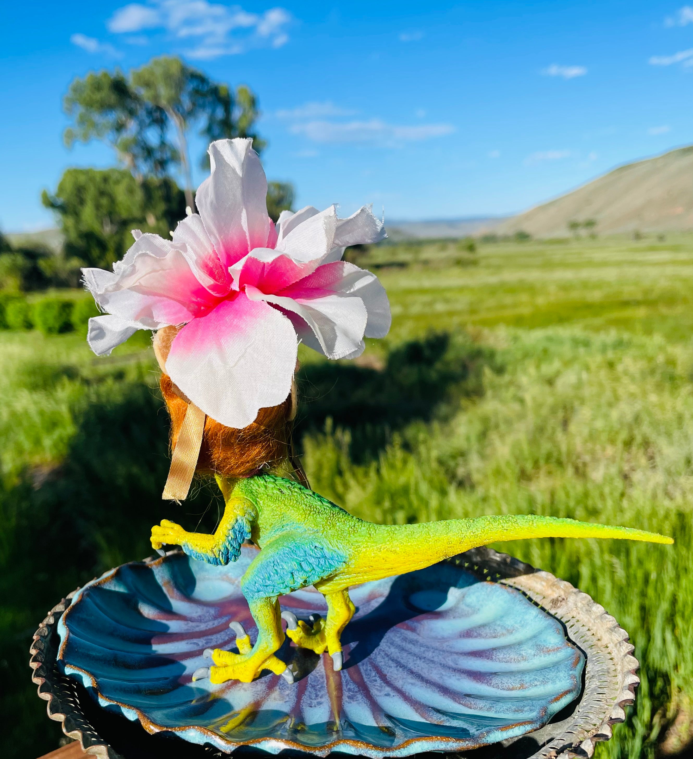 Backside. Vintage doll head with flower headdress on toy dinosaur body