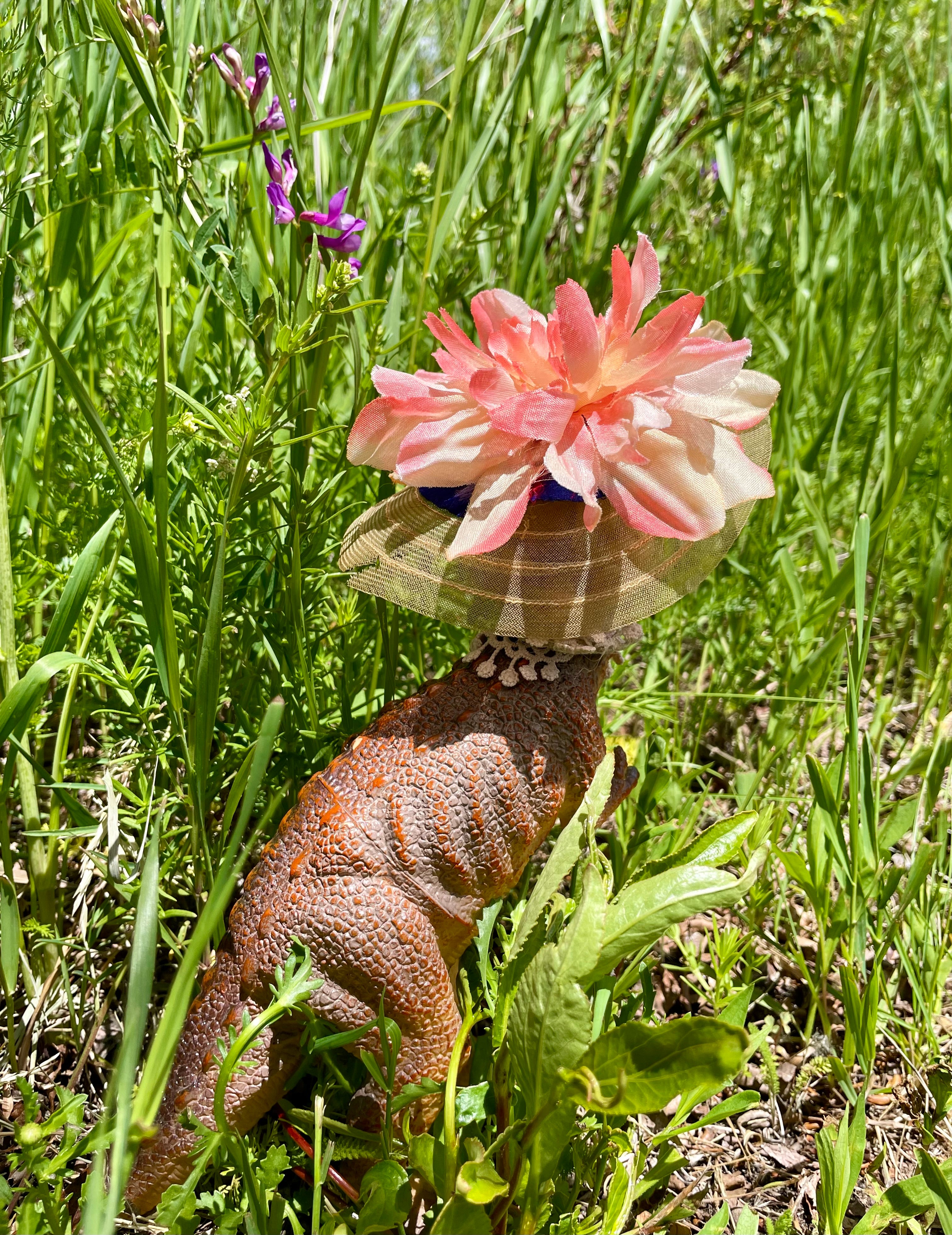 Backside, Vintage toy dinosaur body with Madame Alexander head, floral hat and lace neckline, 10" tall, 3" wide, 8" long.