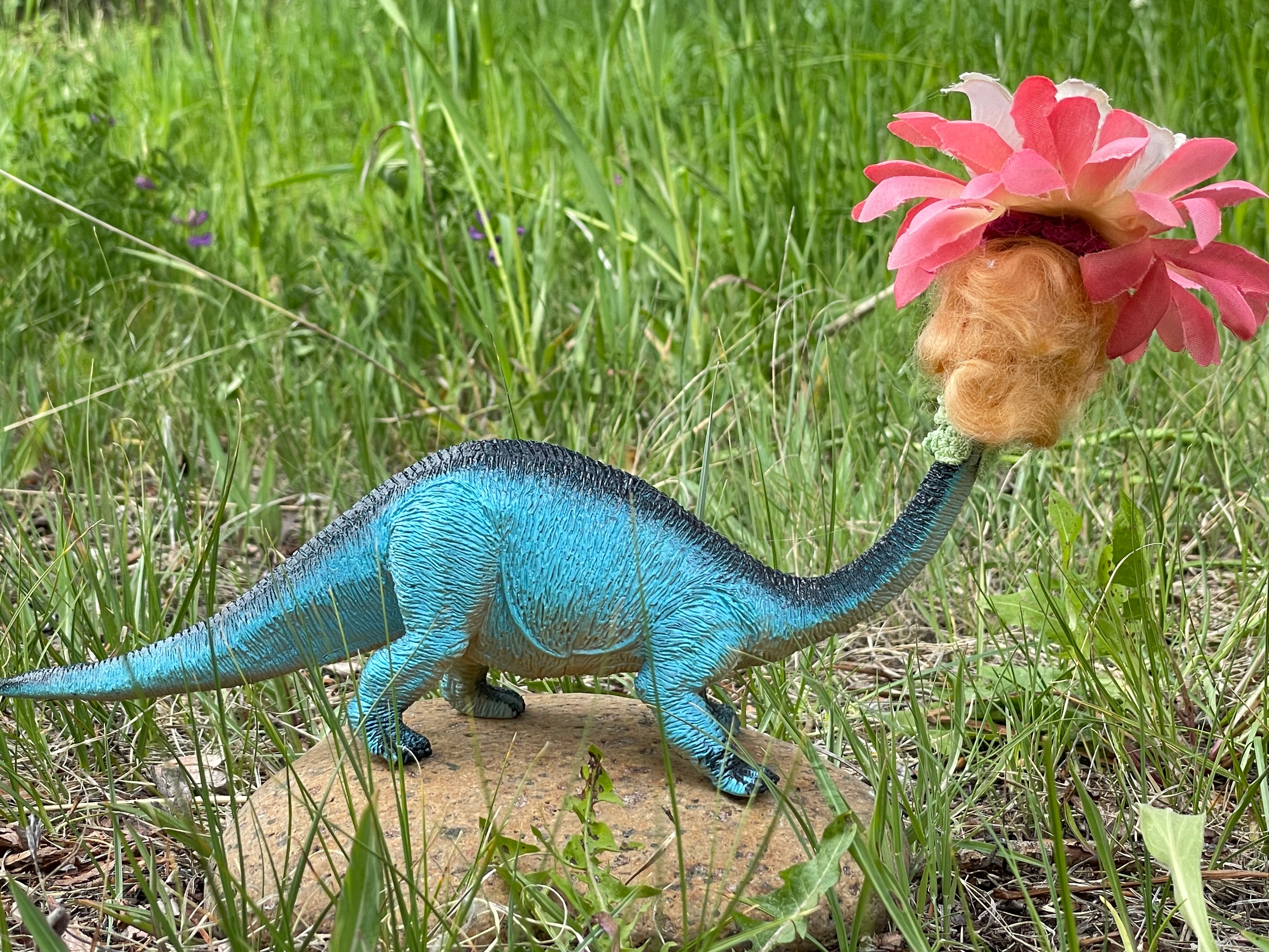 Backside. Vintage toy dinosaur with vintage doll head and flower headdress. 7" long , 5" tall, 2" wide. 