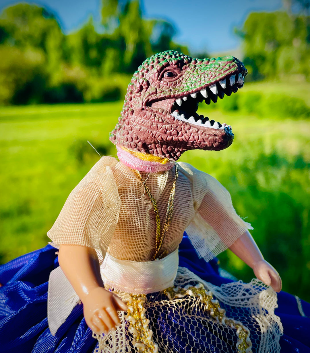 Close up, Vintage doll in a purple satin dress with tulle embellishments and a dinosaur head. 