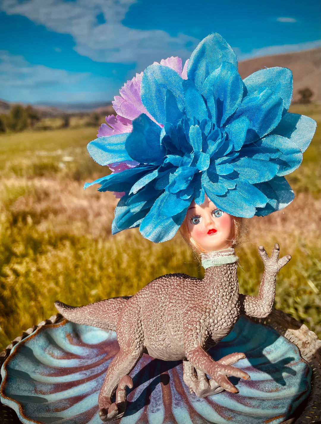 Vintage toy dinosaur with vintage doll head and flower headdress. 5" tall x 5" long x 3" wide.
