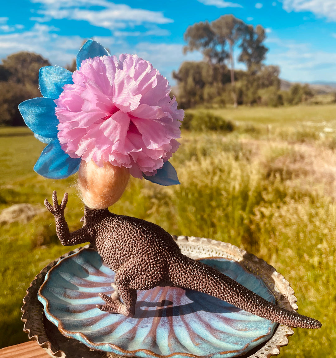 Vintage toy dinosaur with vintage doll head and flower headdress. 5" tall x 5" long x 3" wide.