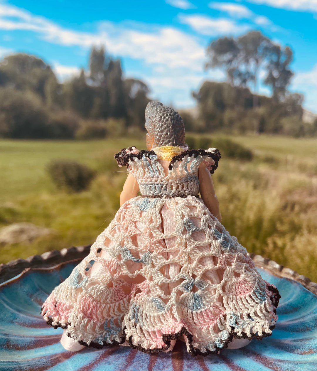 Backside, Vintage doll in a pastel crochet dress, satin petticoat with a dinosaur head. 4" tall x 3" wide