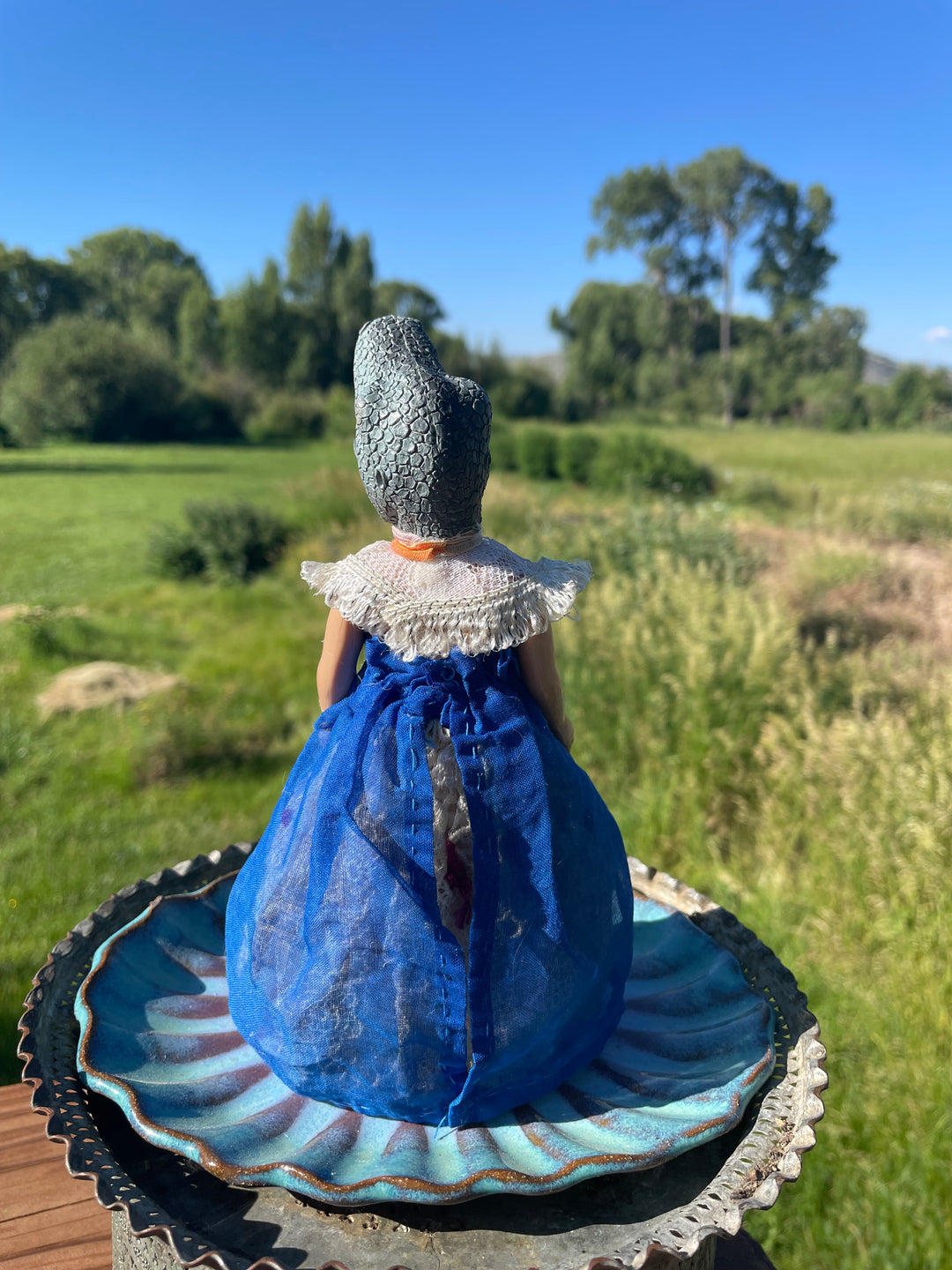 Backside, Vintage toy doll with a dinosaur head. Hand dyed blue gauze skirt over a lace pinafore with a lace bib collar. 6" tall x 3" wide.